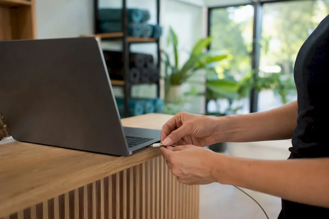 Hands plugging charger into device at studio desk